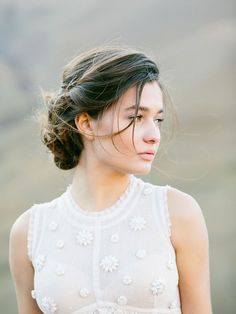 a woman wearing a white dress with flowers in her hair is looking off to the side