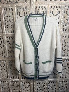 This medium-sized ladies cardigan features a cream-colored button-up design with navy and light green stripe accents on the sleeves for a stylish and modern look. Perfect for chilly days, this sweater is sure to keep you warm and cozy. Ladies Cardigan, Button Cardigan, Green Button, Green Stripes, Cardigans For Women, Warm And Cozy, Light Green, Button Up, Boutique