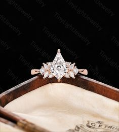 an engagement ring with a princess cut diamond in the center on top of a wooden box