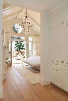 a bedroom with white walls and wooden floors has a chandelier hanging from the ceiling