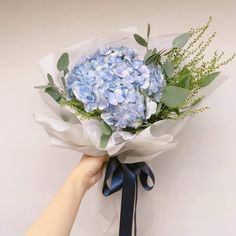 a hand holding a bouquet of blue flowers