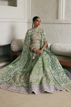 a woman in a green lehenga sitting on the floor