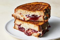 two grilled cheese sandwiches on a white plate with cranberry sauce in between