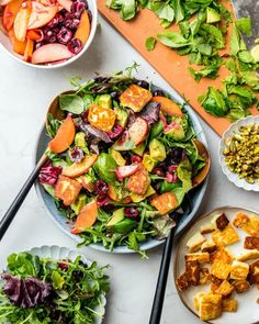 a table topped with plates and bowls filled with salad