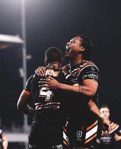 two rugby players hugging each other on the field