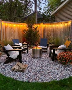 a fire pit surrounded by chairs and lights in a back yard with gravel around it