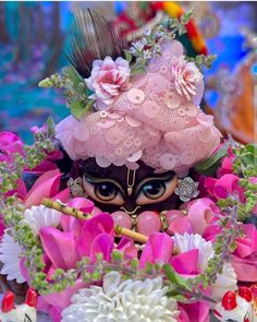 a close up of a doll surrounded by flowers