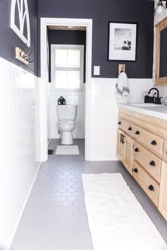 a white toilet sitting in a bathroom next to a sink under a mirror on top of a wooden cabinet