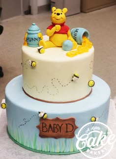 a winnie the pooh cake with honey pot and baby's name on it