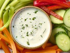 a white plate topped with carrots, cucumber and dip surrounded by other vegetables