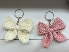 two crocheted keychains with bows on them sitting next to each other