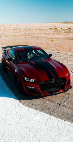 a red and black sports car parked in the middle of an empty desert area with no one around it