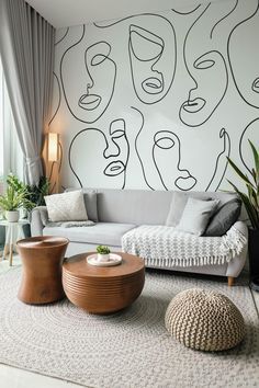 a living room with couches, tables and potted plants in front of a wall mural