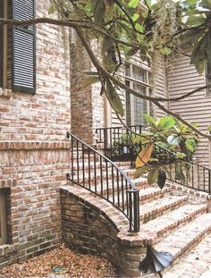 a brick house with black iron railing and stairs