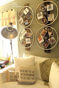 a living room filled with white furniture and pictures hanging on the wall above it's headboard