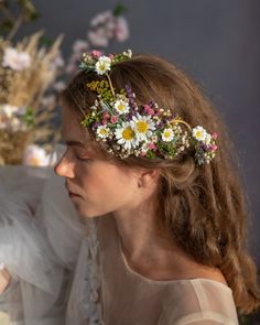 a woman with flowers in her hair wearing a flower crown on her head and dress