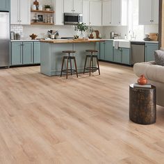 an open kitchen and living room area with wood flooring, blue cabinets and stainless steel appliances