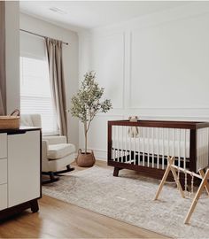 a baby's room with a crib, rocking chair and dresser in it