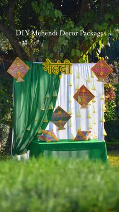 a decorated stage with green drapes and white curtains in the middle of a grassy area