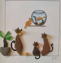 there are three cats that are standing in front of a fish bowl and some rocks