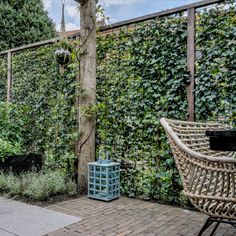 an outdoor patio with wicker furniture and greenery on the fenced in area