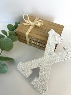 a wooden box with a small white letter on it next to some leaves and a plant