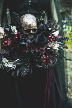 a woman wearing a black dress holding a bouquet with flowers and a skull on it