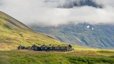 a group of houses sitting on top of a lush green hillside next to a mountain