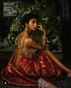 a woman sitting on the floor in a red sari with jewelry around her neck