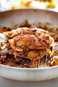 a close up of food in a pan with a spatula being lifted from it