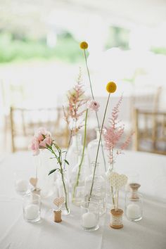 vases filled with flowers on top of a white table cloth covered dining room table