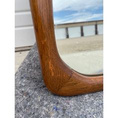 a wooden mirror sitting on top of a rock next to a building with a beach in the background