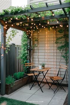 Cozy patio with a wooden table and chairs under a pergola adorned with string lights and plants.