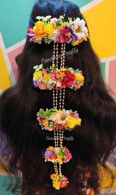 the back of a woman's head with flowers and pearls in her long hair