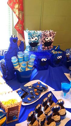 a blue table topped with cookies and cupcakes