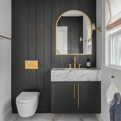 a white toilet sitting under a bathroom mirror next to a sink and a bath tub