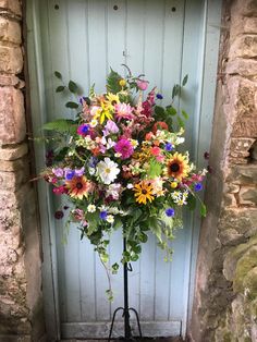 a bouquet of flowers sitting on top of a metal stand in front of a door