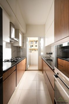 a long narrow kitchen with wooden cabinets and black counter tops, along with white tile flooring