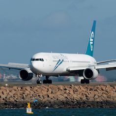 an airplane is taking off from the runway by the water and some people are standing near it