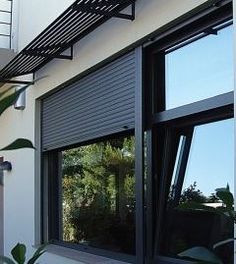 an outside view of a building with some plants in the foreground and a balcony above it