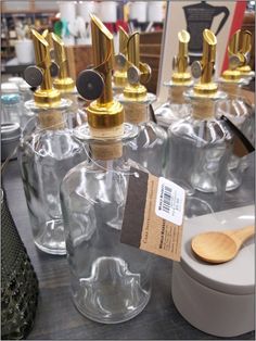 several glass bottles with wooden spoons and tags on them are sitting on a table