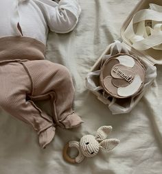 a baby laying on top of a bed next to a bag and two stuffed animals