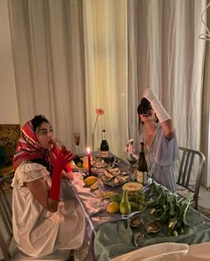 two people sitting at a table with food and wine