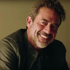 a smiling man in a black leather jacket