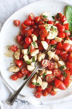 a white plate topped with sliced tomatoes and chicken