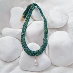 a close up of a necklace on a white surface with rocks in the foreground