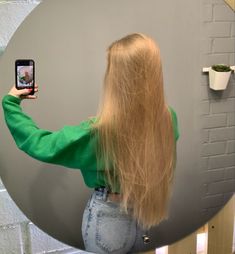 a woman taking a selfie with her cell phone in front of a circular mirror