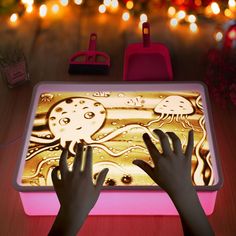 two hands reaching for an illuminated tablet on a table