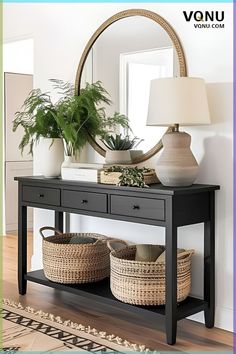 a black console table with two baskets on it and a round mirror in the background