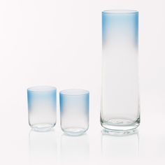 three glass vases sitting next to each other on a white surface with one empty